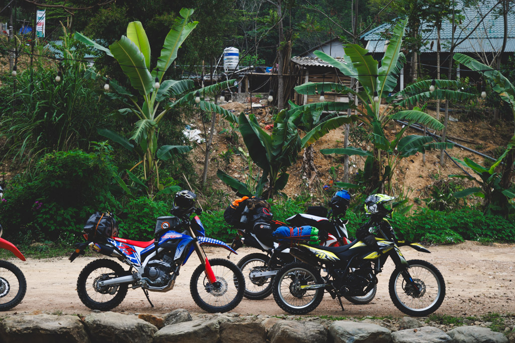 Line up of some lightweight adventure bikes along a dirt trail in the jungle of Vietnam.